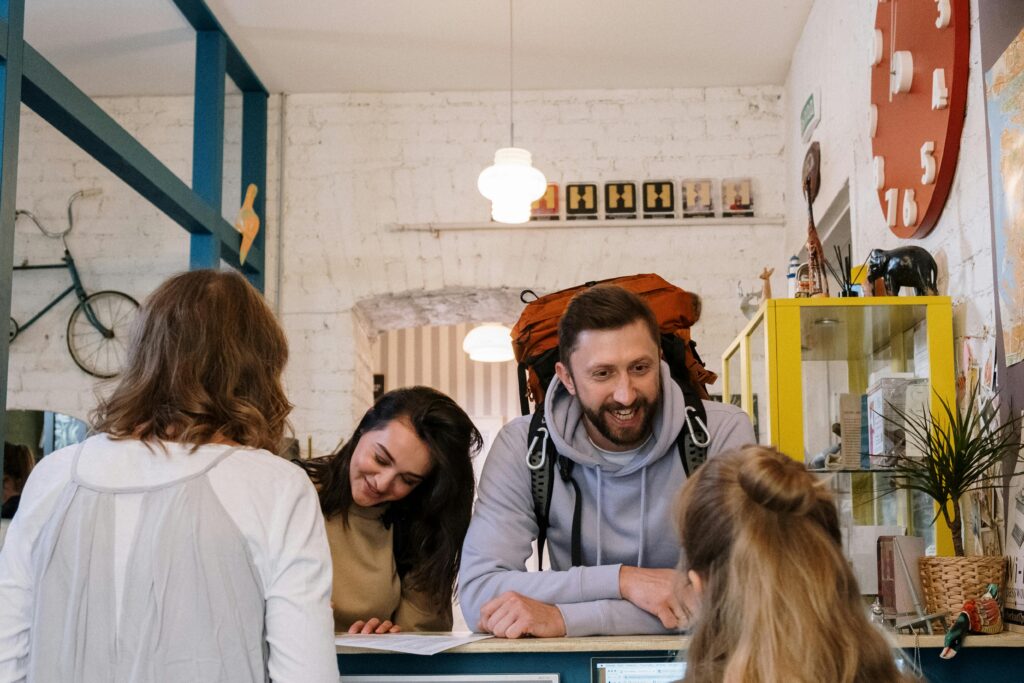 Backpackers cheerfully checking in at a vibrant hostel reception desk.